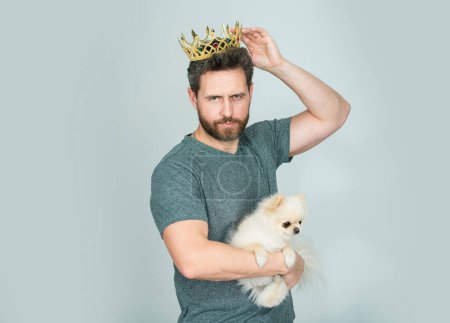 Téléchargez les photos : Homme portant la couronne d'or du roi tient chiot chien. beau barbu guy roi - en image libre de droit