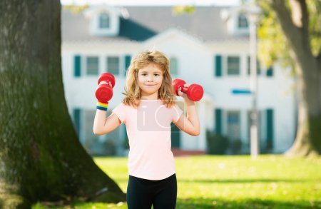 Photo for Kids morning sports exercises. Sporty portrait kids. Fitness child with dumbbells in park. Gym workout. Child sportsman, childhood activity. Kids sport and fitness - Royalty Free Image