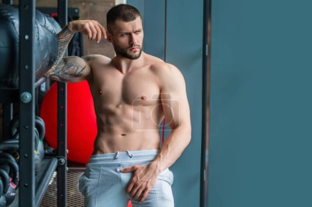 Foto de Fitness man in the gym. Young muscular man workout. Man with sexy strong body, strength and motivation. Fitness man at workout in gym pumping up muscles. Fitness and bodybuilding health - Imagen libre de derechos
