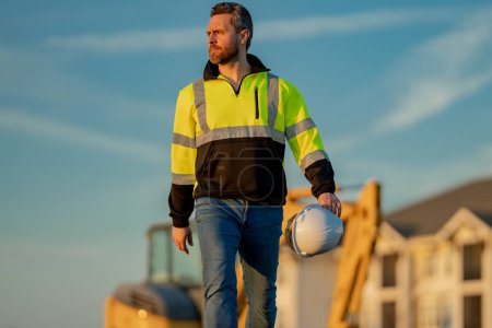 Photo for Worker in helmet on site construction. Excavator bulldozer male worker. Construction driver worker with excavator on the background. Construction worker with tractor or construction at building - Royalty Free Image