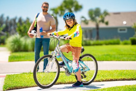 Photo for Father and son in a helmet riding bike. Little cute adorable caucasian boy in safety helmet riding bike with father. Family outdoors summer activities. Fathers day. Childhood and fatherhood - Royalty Free Image