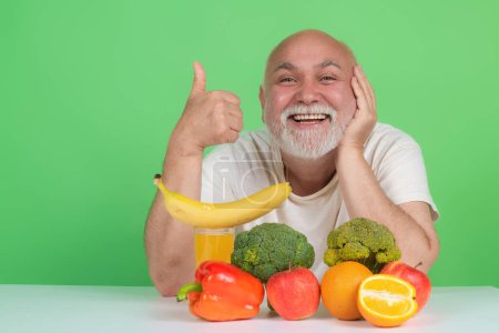 Téléchargez les photos : Boisson senior près des fruits et légumes en studio. Homme âgé sur les fruits et légumes alimentation. Légumes et fruits sains pour les personnes âgées. Mode de vie sain. Fruits âgés Légumes Dieting - en image libre de droit