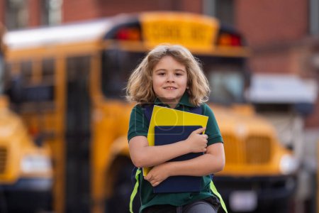 Téléchargez les photos : Enfant avec sac à dos et livre monter dans le bus scolaire. L'école américaine. Je retourne à l'école. Enfant de l'école primaire. Des enfants heureux prêts à étudier. Étudiant prêt à étudier - en image libre de droit