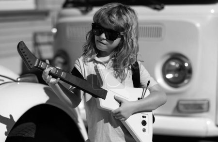 Téléchargez les photos : Child musician playing the guitar like a rockstar outdoor. Kid boy rock musician with guitar. Kid with guitar - en image libre de droit