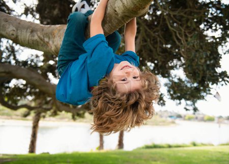 Foto de Un niño pequeño en una rama de árbol. Niño sube a un árbol - Imagen libre de derechos