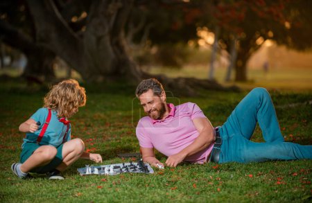 Photo for Father and son playing chess spending time together in park. Sport and hobby concept. Little boy play chess with parent. Cognitive development. Intellectual kids game. Smart children - Royalty Free Image
