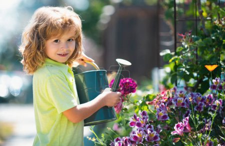 Téléchargez les photos : Enfance américaine. Enfant arrosant des fleurs dans le jardin. Jardinage à domicile. - en image libre de droit
