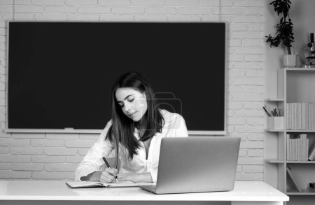 Photo for Female college student working on a laptop in classroom, preparing for an exam - Royalty Free Image