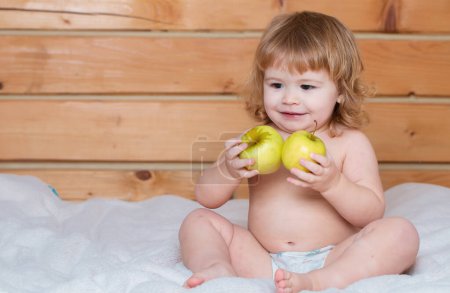 Téléchargez les photos : Bébé mignon manger des pommes. Joyeux petit garçon mangeant des pommes. Enfant avec des fruits frais - en image libre de droit