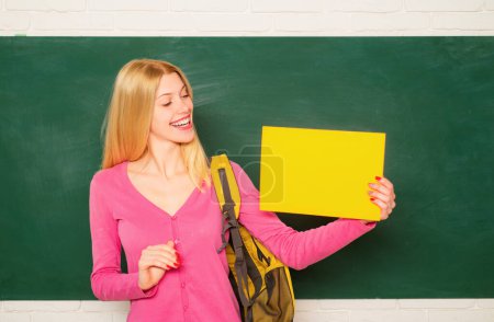 Photo for Female student. Young teacher or tutor at classroom in school. Woman education. Student girl holding empty faper for product - Royalty Free Image