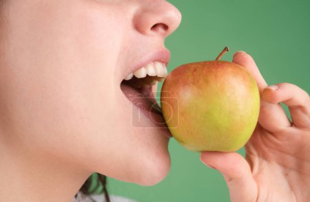 Foto de Una hembra mordiendo una manzana. Mujer boca abierta a punto de morder manzana verde - Imagen libre de derechos