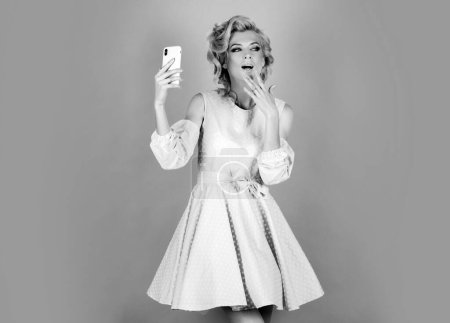 Foto de Retrato de mujer sorprendida usando teléfono móvil. Chica sosteniendo teléfono inteligente sobre fondo rosa. Mujer hermosa joven con teléfono inteligente - Imagen libre de derechos