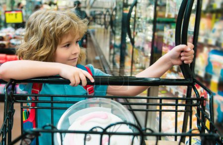 Téléchargez les photos : Enfant avec panier achetant de la nourriture à l'épicerie ou au supermarché - en image libre de droit