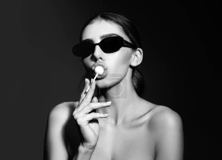 Foto de Sexy woman face. Young glamour sexy girl in sunglasses with lollipop looking at the camera - Imagen libre de derechos