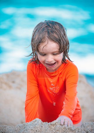 Foto de Niño disfrutando del tiempo en la playa de arena. Niño haciendo castillo de arena en el mar - Imagen libre de derechos