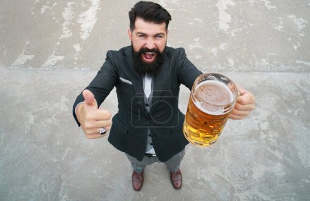 Foto de El barbudo retiene la cerveza de una taza de cerveza. Longitud completa, gran ángulo. Emociones de expresión - Imagen libre de derechos