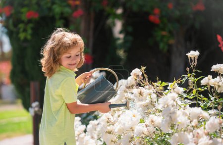 Téléchargez les photos : Enfance américaine. Enfant arrosant des fleurs dans le jardin. Jardinage à domicile. - en image libre de droit
