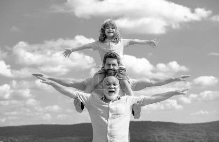 Foto de Grandfather with son and grandson having fun, raising hands or open arms flying on sky. Start, creativity startup concept - Imagen libre de derechos