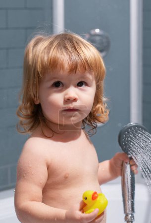 Téléchargez les photos : Petit enfant se baignant dans des savons. Bébé enfant lavage dans une salle de bain en mousse - en image libre de droit