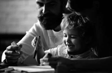 Photo for Happy family mother father and child son drawing laughing. Early childhood education, kids creative growth. Parents and their little child painting writing in book with pencil making homework at home - Royalty Free Image