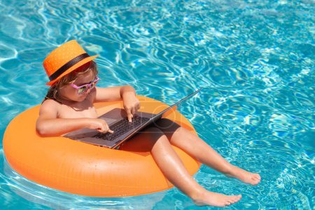 Photo for Summer business and online technology. Child sitting in swimming ring in pool and using laptop. Shopping online, freelance concept, summer travel - Royalty Free Image