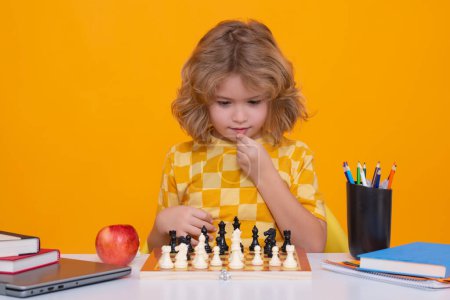 Foto de Niño jugar ajedrez en el fondo del estudio. Un chico pensando en ajedrez. El concepto de aprendizaje y crecimiento de los niños. Ajedrez, éxito y ganar. Juego de lógica de mesa, pasatiempo para niños y estilo de vida - Imagen libre de derechos