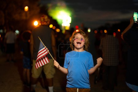 Foto de Un niño excitado sostiene la bandera americana. Vacaciones patrióticas. Niño con bandera americana en Washington DC. Los niños estadounidenses celebran el día de la independencia 4 de julio. Retrato de niño americano con bandera americana - Imagen libre de derechos