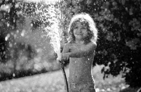 Photo for Kid having fun in domestic garden. Child hold watering garden hose. Active outdoors games for kids in the backyard during harvest time - Royalty Free Image