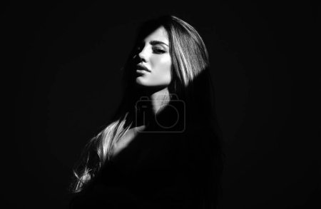Photo for Sensual girl with art shadow light. Sensual woman with light on a black background. Beautiful female face in the darkness. Tender and seductive look. Fashion art studio portrait - Royalty Free Image