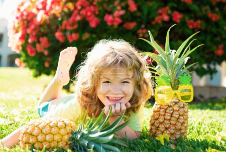 Photo for Happy smiling kid boy holds pineapple in hands, child and tropical fruits - Royalty Free Image