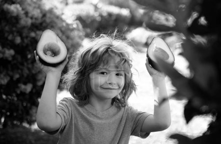 Photo for Kid eating and enjoying an avocado on a nature background. Healthy food for kids concept - Royalty Free Image