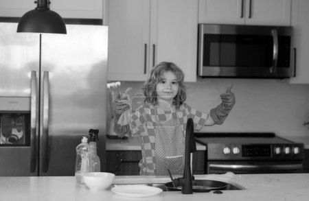 Photo for Child cleaning dishware kitchen sink sponge washing dish. Kid wiping dishes in kitchen. Child cleaning and doing housework at home. Cute boy helping with housekeeping in kitchen, cleaning - Royalty Free Image