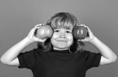 Photo for Funny kid boy hold a red apple and a green apple. Isolated on studio background - Royalty Free Image