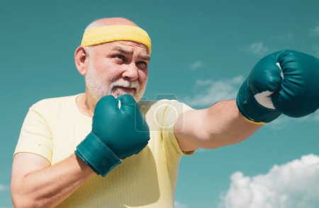 Photo for Handsome elderly man practicing boxing kicks. Elderly man hitting punching bag. Senior men fighting poses. Senior sport man wearing boxing gloves - Royalty Free Image