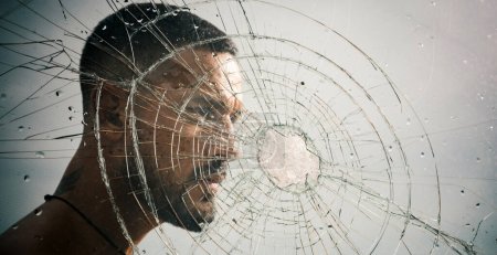 Photo for Crack. macho man behind crushed glass. anger. destruction. crush test. theft. emotional discharge. bullet hole in glass. broken glass because of hit. sexy hispanic man broken mirror. crack in glass. - Royalty Free Image