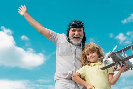 Téléchargez les photos : Grand-père et petit-fils jouant avec l'avion jouet sur fond de ciel d'été - en image libre de droit