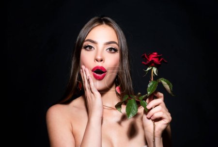Foto de Mujer sorprendida con labios rojos y flor de rosa. Retrato de belleza de moda en el fondo del estudio - Imagen libre de derechos