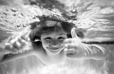 Téléchargez les photos : Enfants jouant dans la piscine. Enfant nageant sous l'eau dans la piscine. Des gosses drôles. Les enfants nagent dans l'eau de mer. drôles excités enfants visage sous l'eau - en image libre de droit