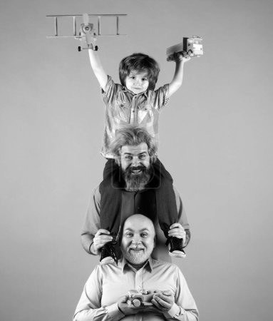 Téléchargez les photos : Un gamin qui s'amuse avec un jouet. Hommes génération famille avec trois générations différentes âges grand-père père et fils. Voyage voyage concept voyage - en image libre de droit