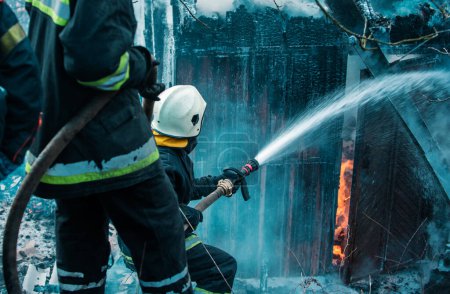 Foto de Bomberos apagando un incendio en la casa - Imagen libre de derechos