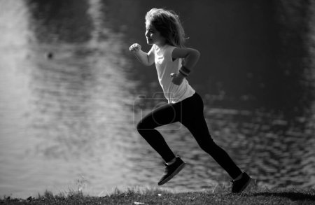 Téléchargez les photos : Les enfants garçons coureurs courent dans le parc. Jeune enfant sportif faisant du jogging et s'entraînant en plein air. Course matinale avec enfants - en image libre de droit