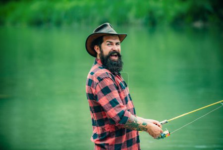 Téléchargez les photos : Pêcheur pêchant sur un rever. Pêcheur détendu homme avec une canne à pêche un jour d'été - en image libre de droit