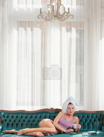 Photo for Girl resting and laying in cozy sofa bed in the luxury bedroom an easy morning. Attractive sexy woman relaxing wearing bathrobes and towels in hotel - Royalty Free Image