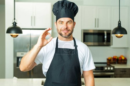 Photo for Chef cook with ok sign, delicious food. Portrait of chef man in a chef cap in the kitchen. Man wearing apron and chefs uniform and chefs hat. Character kitchener, chef for advertising - Royalty Free Image