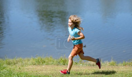 Photo for Healthy sport activity and running for children. Little boy at race. Young athlete in training. Kid boy running on green grass near lake in summer park - Royalty Free Image