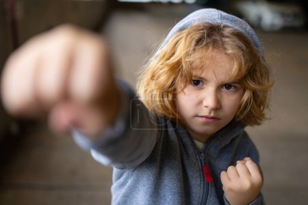 Photo for Aggressive bad child. Kid boy in hoodie fighting. Little kid boy fight outdoor. Angry boy fighting fist. Bad kids. Portrait of fighting kid. Bad Children fight. Aggression little boy. Bad behavioral - Royalty Free Image