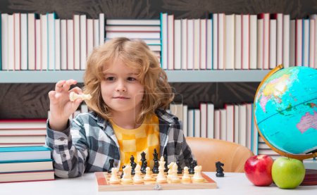 Téléchargez les photos : Un gamin joue aux échecs à l'école. Un gamin joue aux échecs. Enfant pensant. Jeu d'échecs pour les enfants. Intelligent, intelligent et intelligent garçon d'école - en image libre de droit