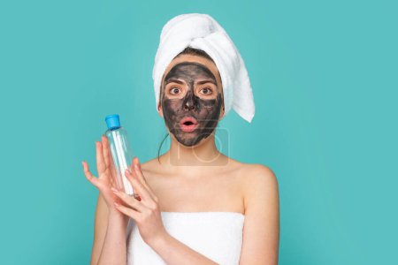 Téléchargez les photos : Facial treatment. Beautiful young woman with charcoal mud facial mask on face. Skin care and treatment. Facial black clay mask - en image libre de droit