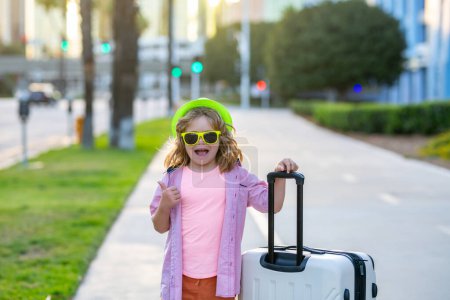 Foto de Los niños viajan y viajan fin de semana. Los niños viajan. Niño feliz llevando maletas al aire libre en la calle de la ciudad. Sueños de viaje - Imagen libre de derechos