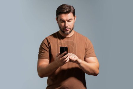 Photo for Portrait of a cheerful man using mobile phone isolated over studio background. Caucasian man using smart phone cellphone for calls, social media, mobile app. Online chatting. Guy talking on the phone - Royalty Free Image